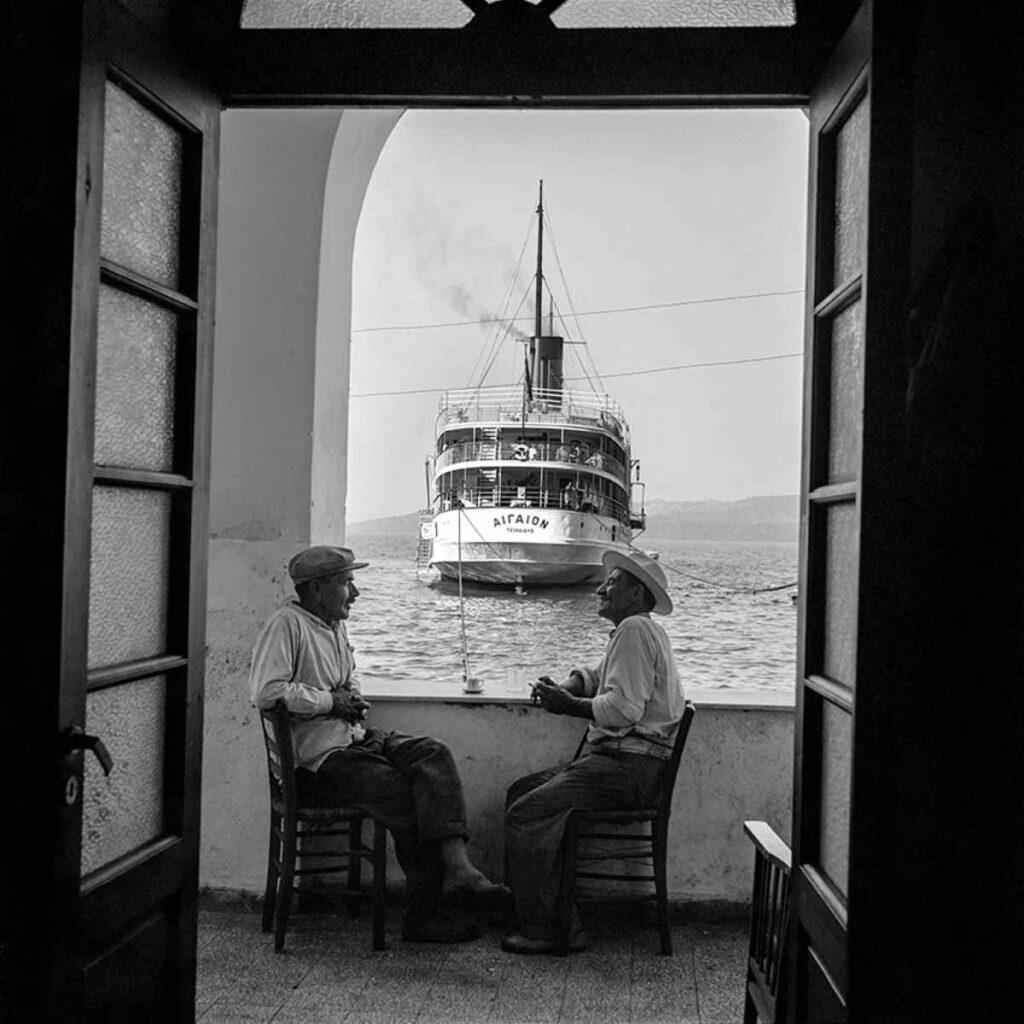 1-Ο καπετάνιος Γιάννης «Τρικούλης» Καφιέρης (αριστερά) και ο Μανόλης «Καστοριάς», ημιονηλάτης από το Κοντοχώρι, ξεκουράζονται στο καφενείο στον Γιαλό, λιμάνι των Φηρών